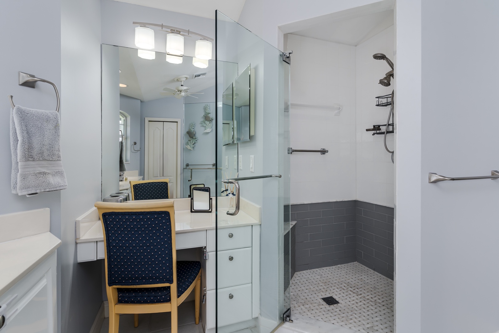 This sleek bathroom features a walk-in shower with modern tiling, a vanity with seating, and bright lighting—your private retreat for unwinding after a day of adventure.