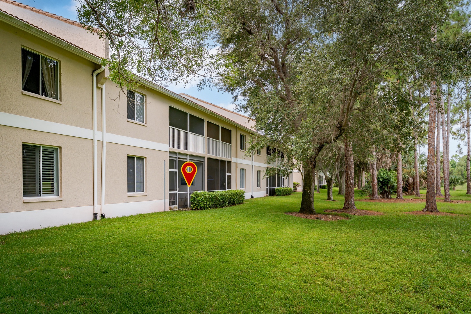 A two-story rental property surrounded by mature trees and lush green lawns, offering a peaceful retreat in a natural, park-like setting.