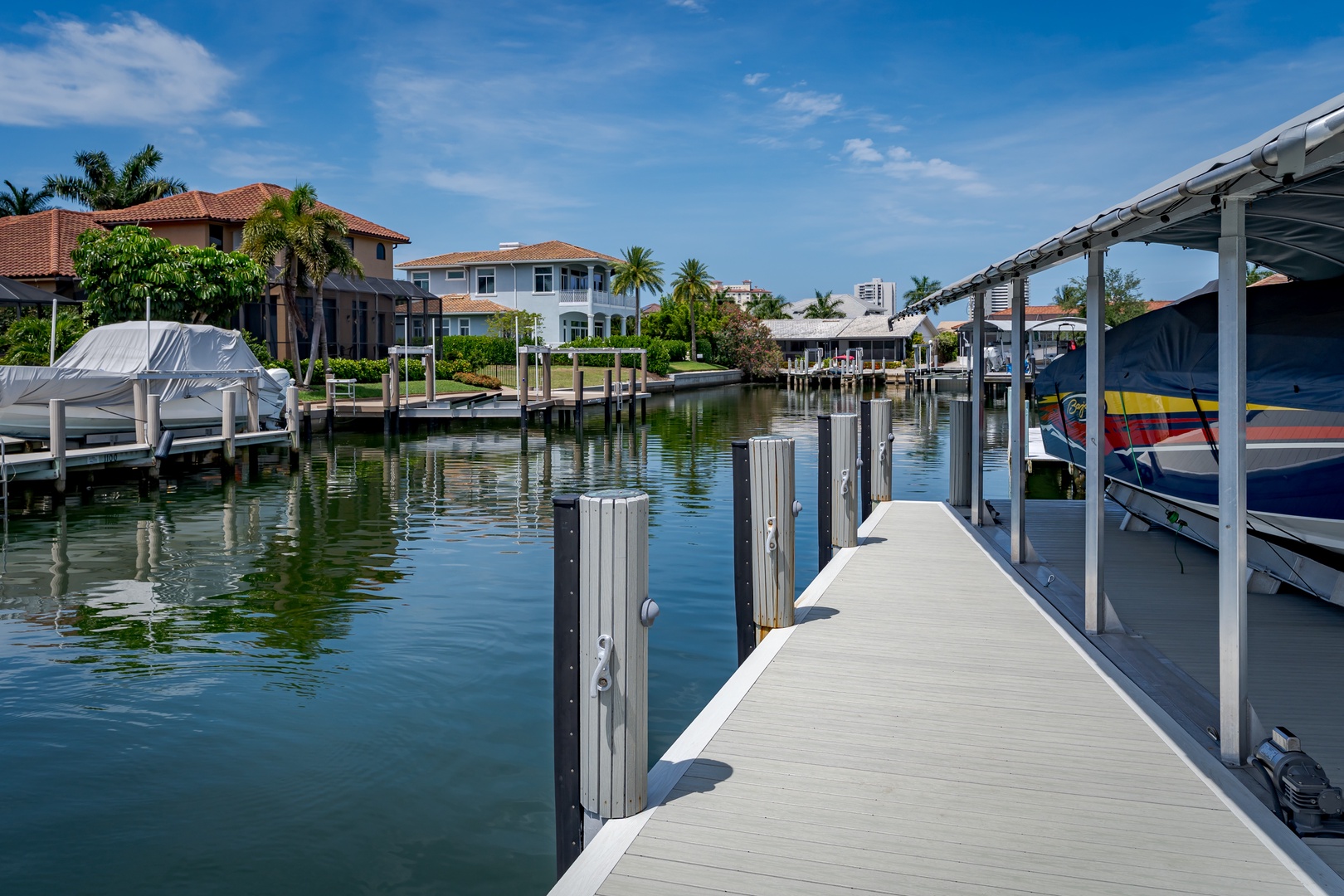 Waterfront neighborhood with private dock access and boat lift, set against lush landscaping and Mediterranean-style homes along calm canal waters.