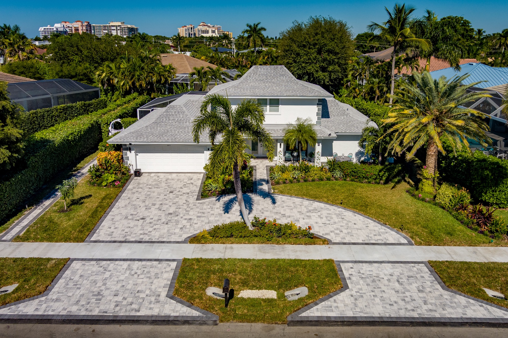 A modern white house nestled in lush tropical surroundings with manicured landscaping and convenient driveway parking in a peaceful residential setting.