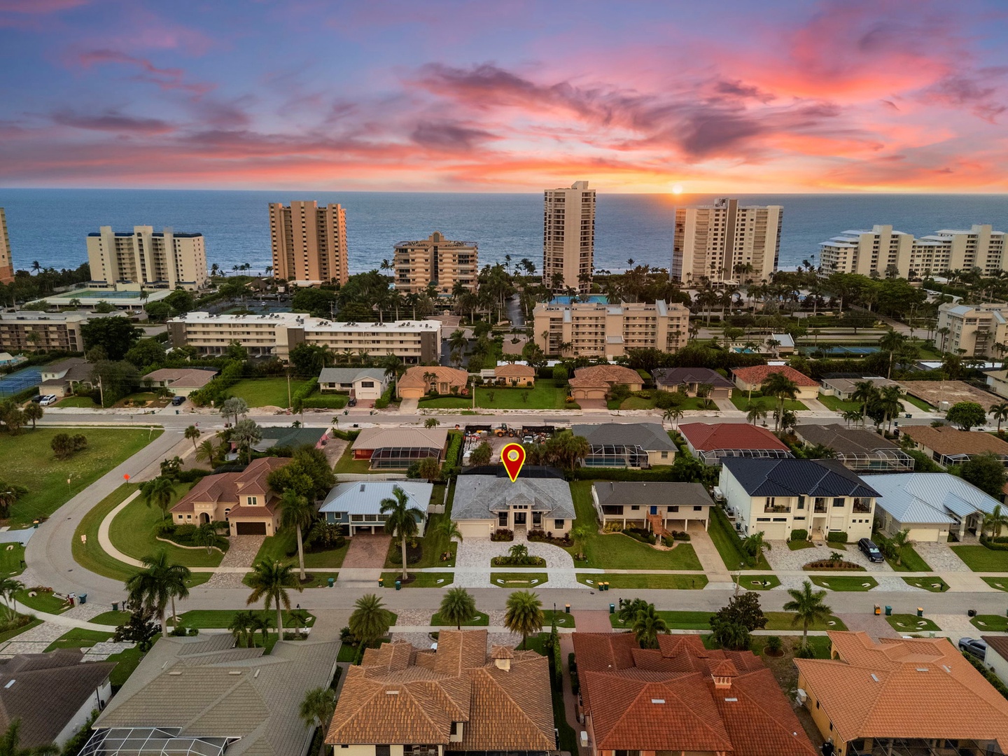 Aerial view of this beachside neighborhood at sunset, just blocks from the ocean. Prime location in a peaceful coastal community with palm trees and nearby high-rises.