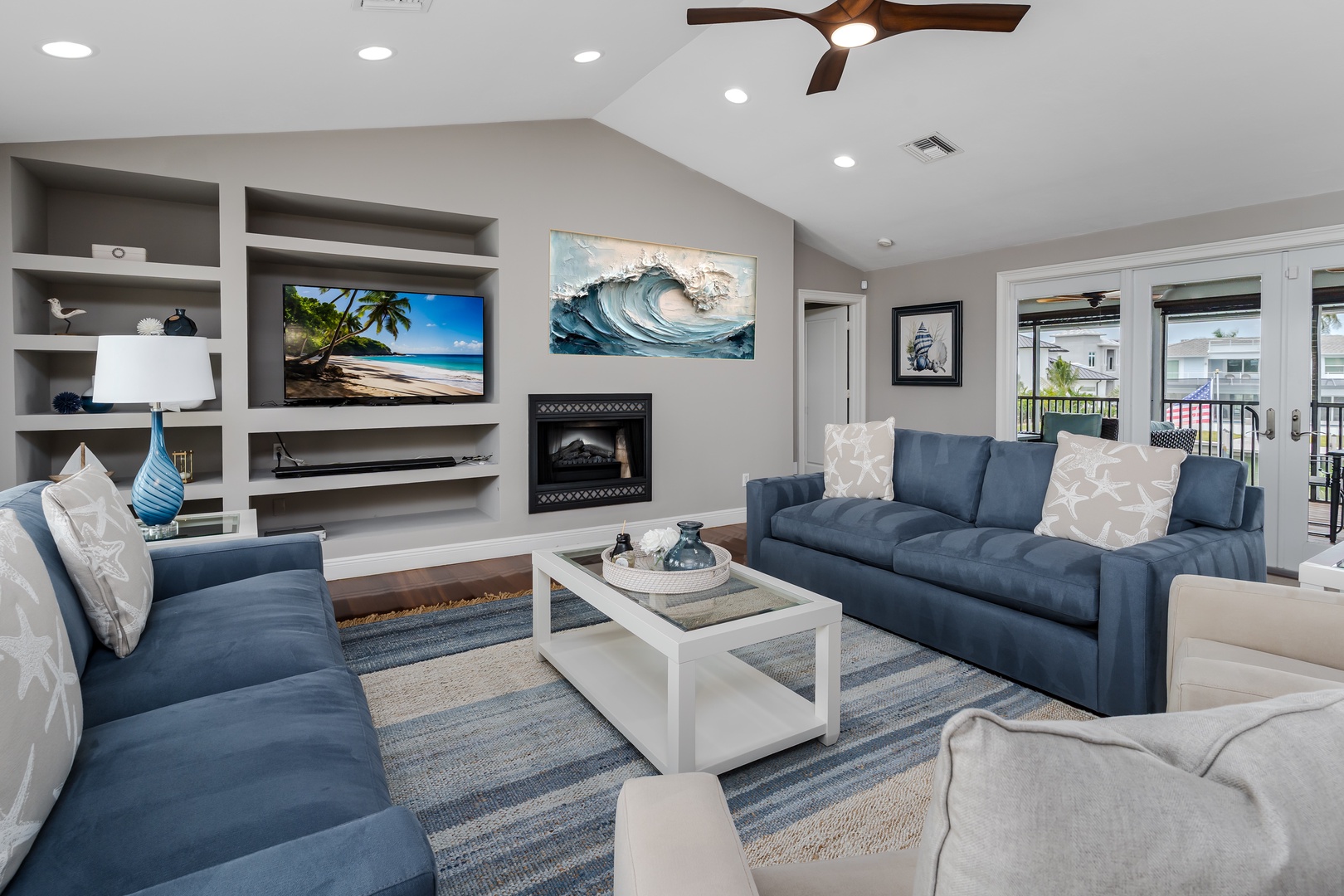 Sink into plush blue sofas and unwind in your bright coastal living space, where ocean-inspired art, a cozy fireplace, and plenty of natural light create the perfect retreat after a day of adventure.