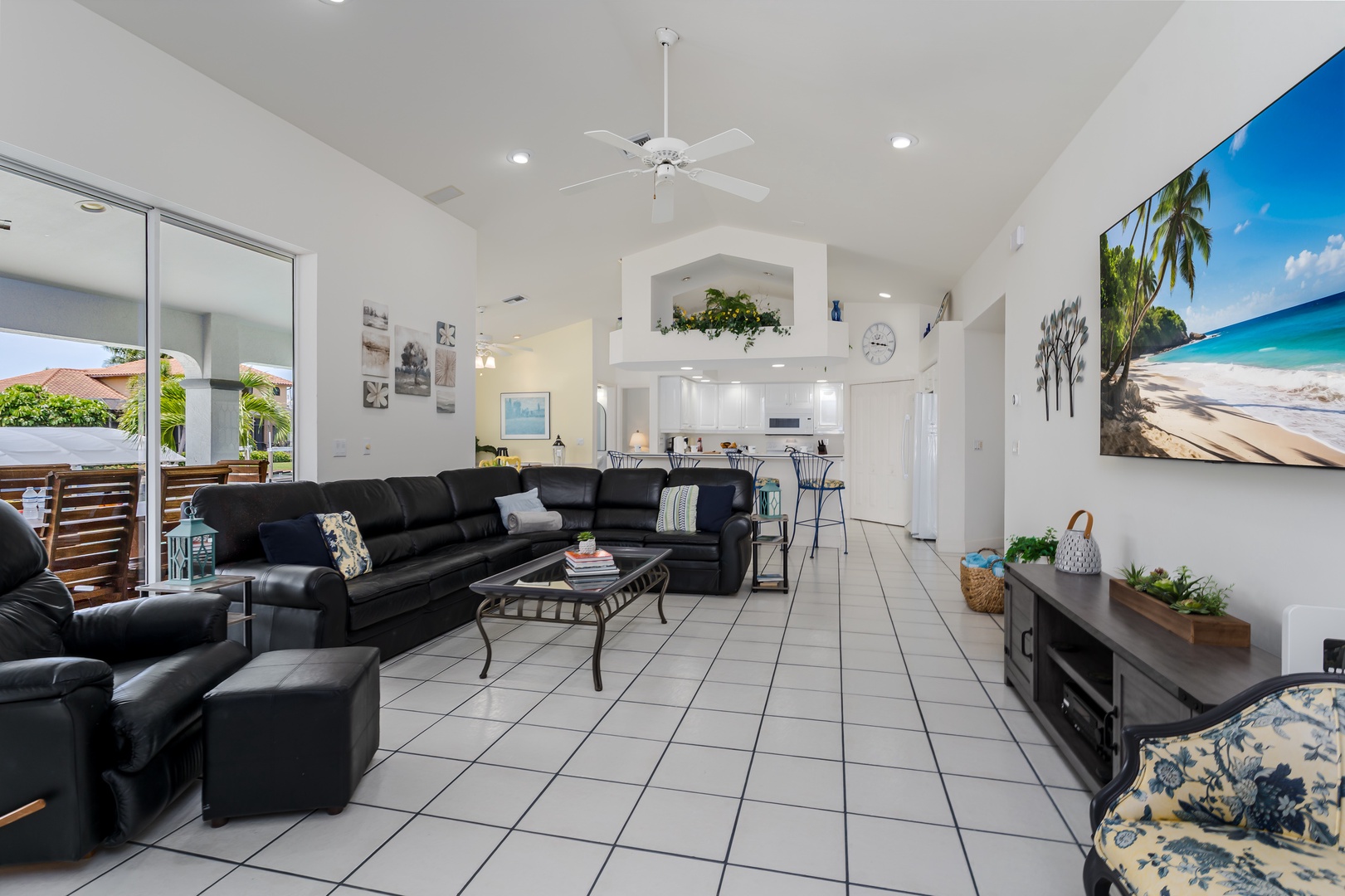 Relax in your spacious, light-filled living room with vaulted ceilings, plush leather seating, and vibrant tropical artwork that sets a vacation mood from the moment you arrive.