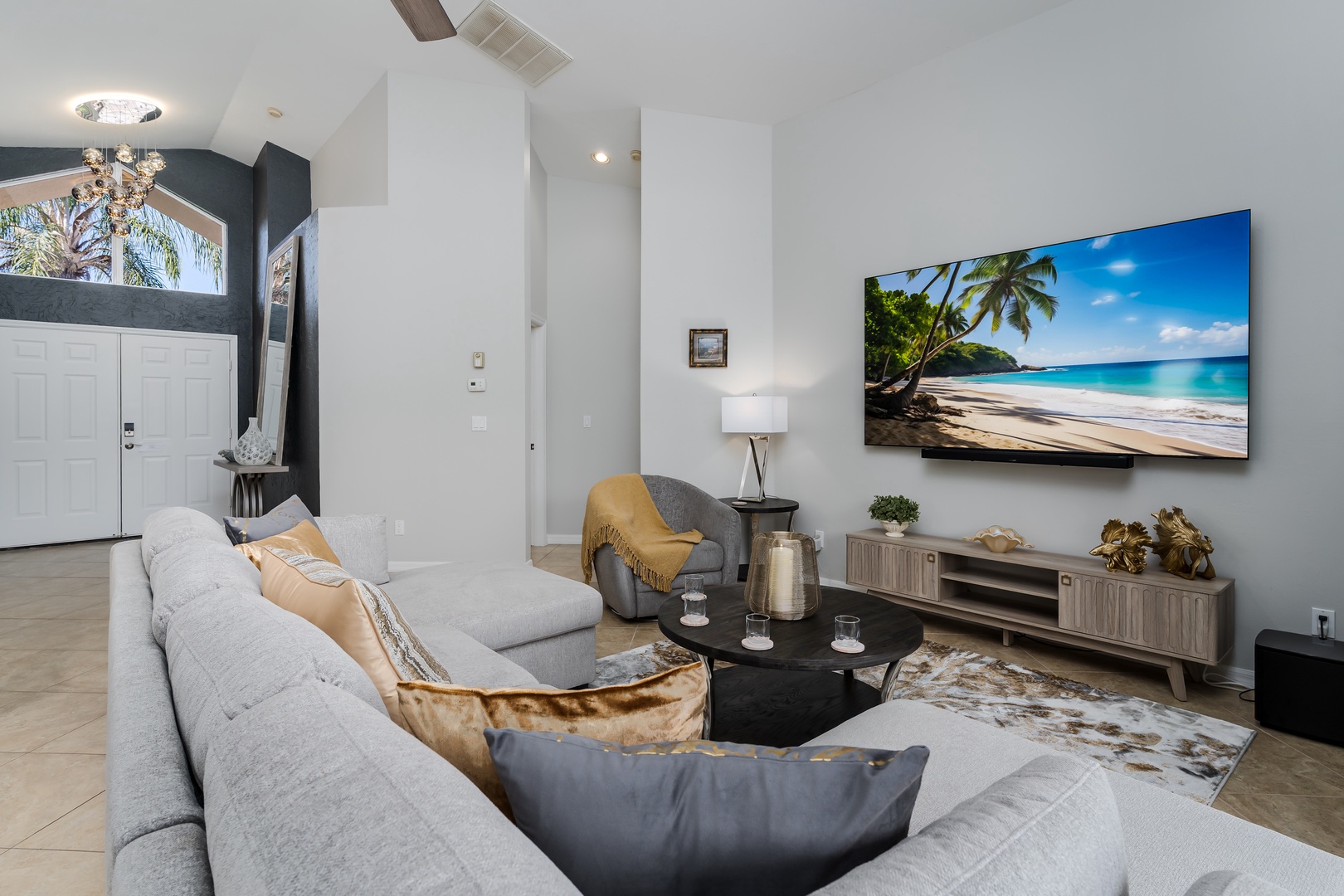 Unwind in your spacious living room featuring plush seating, a large smart TV, and tropical artwork that sets the perfect vacation mood.