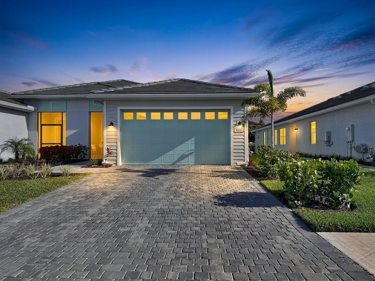 Modern single-story home with a warm welcome awaiting your arrival, set in a peaceful residential neighborhood with lush tropical landscaping and a spacious brick-paved driveway.