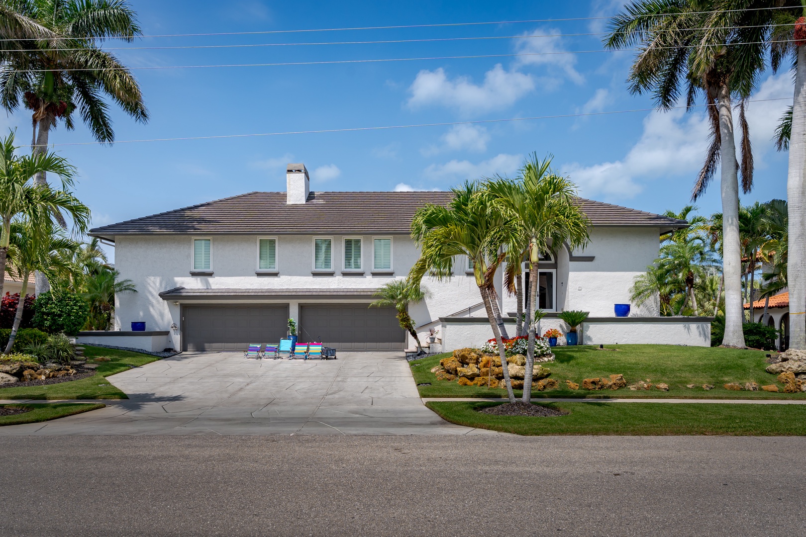 Contemporary two-story property situated in a tropical neighborhood with mature palm trees and manicured landscaping throughout the residential area.