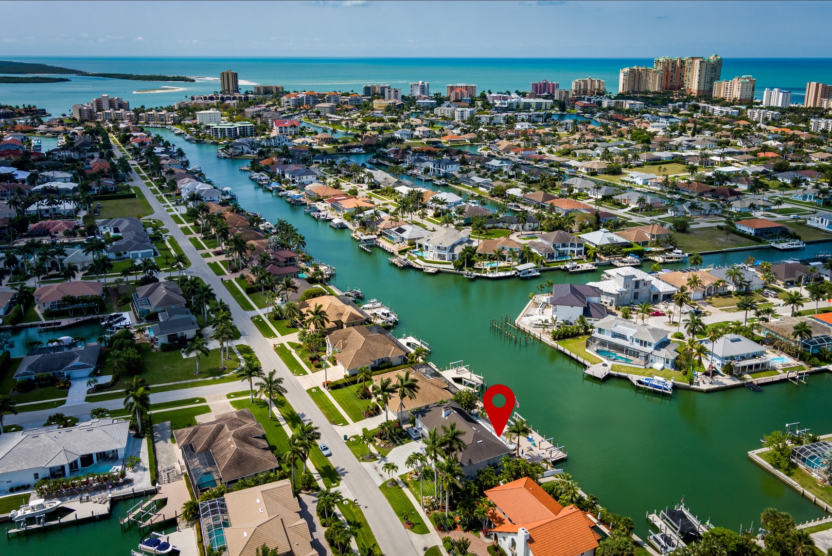 Aerial view of a waterfront community with canal-front homes, private docks, and proximity to the turquoise Gulf waters and nearby beaches.