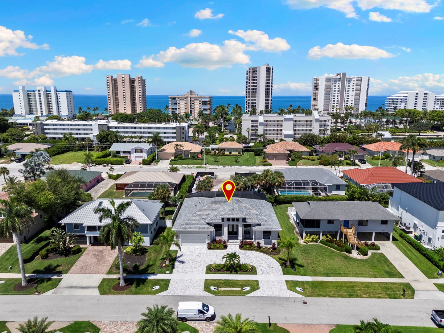 This coastal property sits in a residential neighborhood with ocean views and beach access nearby, surrounded by palm trees and just a short distance from waterfront high-rises.