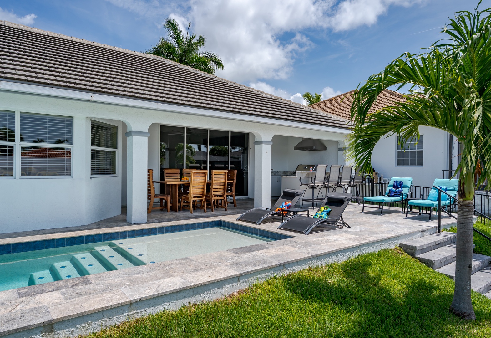 Relax poolside in your private outdoor oasis, complete with lounge seating, dining space, and built-in BBQ under tropical skies—perfect for sunny Florida days.