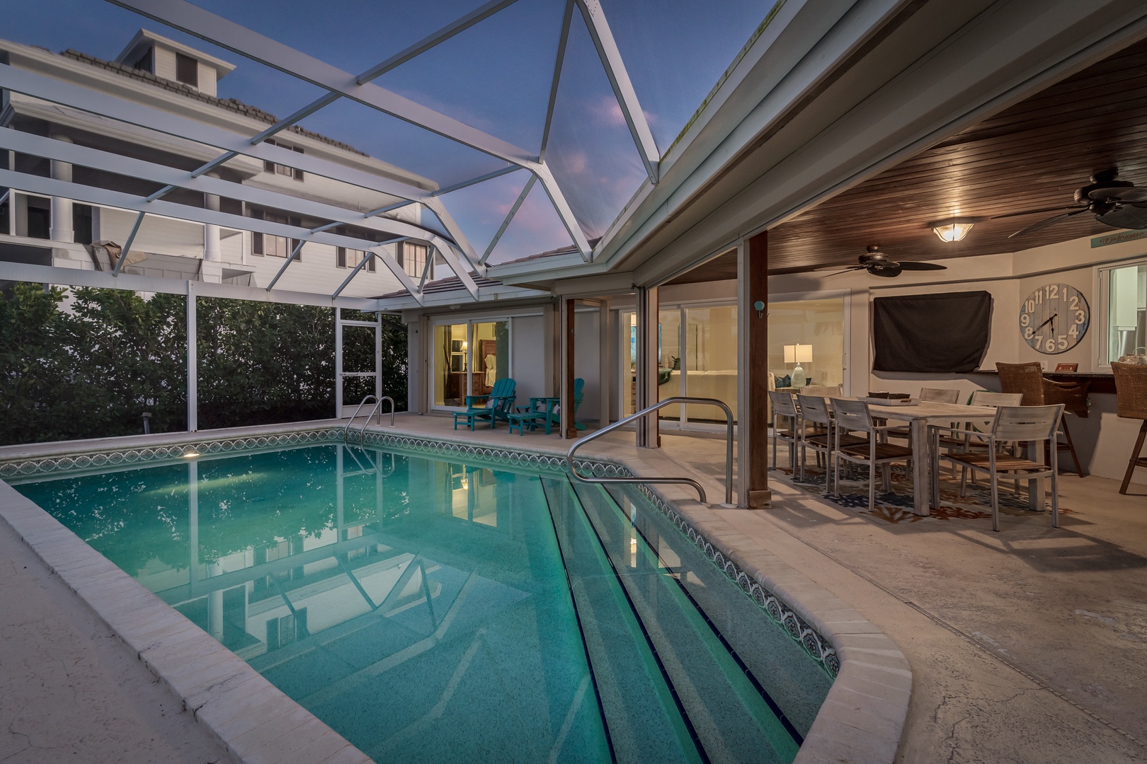 Your private screened pool creates the perfect evening oasis, seamlessly flowing into elegant indoor dining spaces for unforgettable vacation moments.