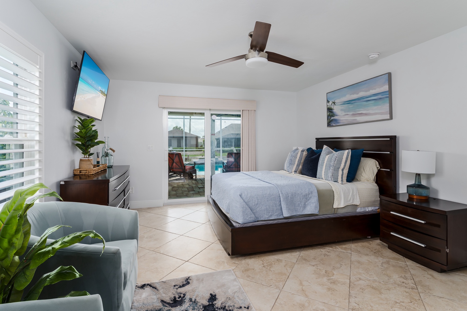 Unwind in your spacious bedroom featuring a comfortable king bed, ceiling fan, and tropical artwork that sets the perfect vacation mood.