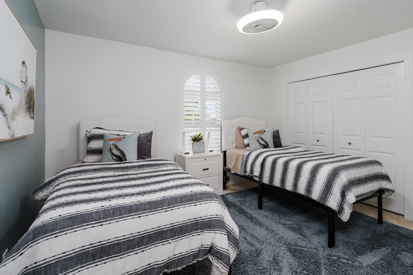 Your peaceful retreat features twin beds with stylish striped linens and a soft blue rug underfoot for ultimate comfort.