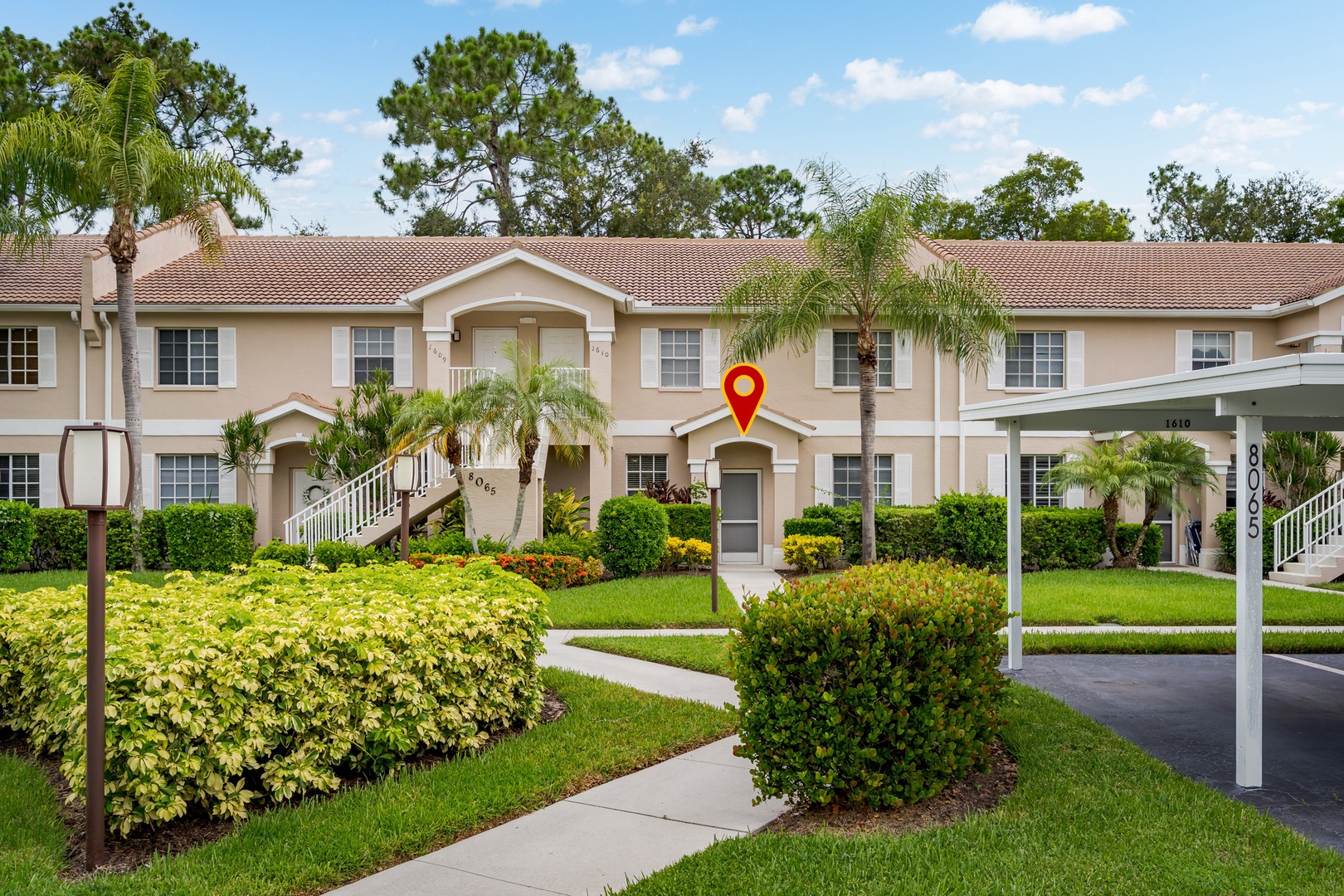 The property features a two-story residential building with a distinctive arched entryway and well-maintained landscaping including palm trees and manicured hedges, set within a peaceful residential neighborhood.