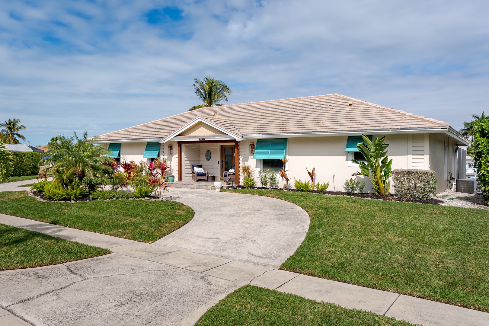 Charming single-story vacation home with tropical landscaping and welcoming front porch in a peaceful residential setting.