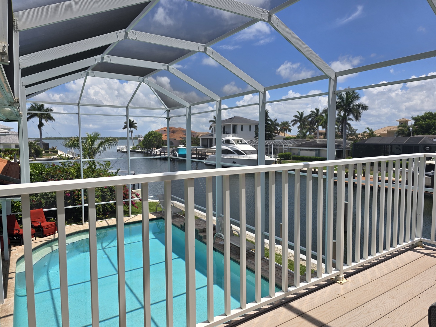 Step onto your private screened balcony overlooking the sparkling pool and scenic waterway with boats and tropical palms.