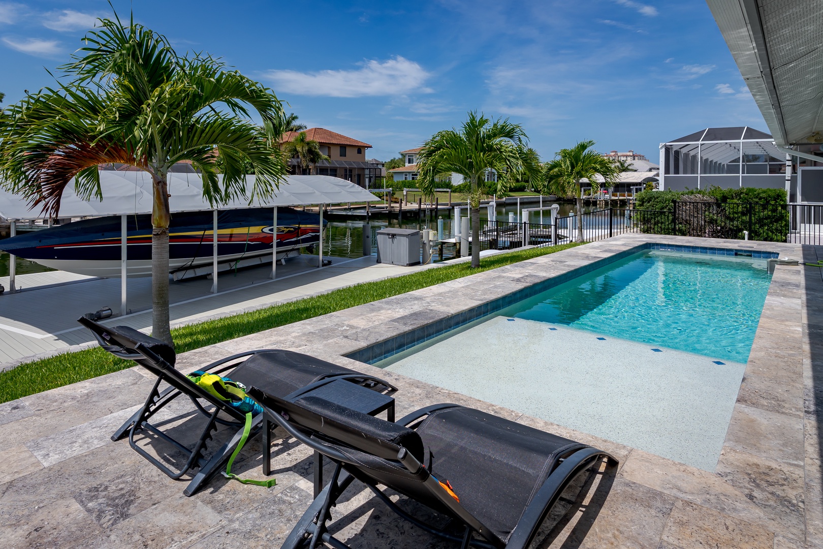 Your private waterfront oasis awaits with sparkling pool, swaying palms, and dock access. Lounge under blue skies, steps from the water.
