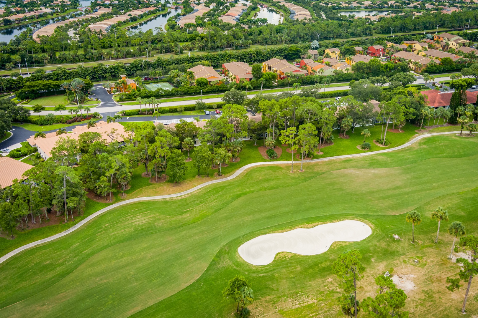 Aerial view of this prime golf course community property, surrounded by lush tropical landscaping and sparkling waterways in a serene, manicured neighborhood.