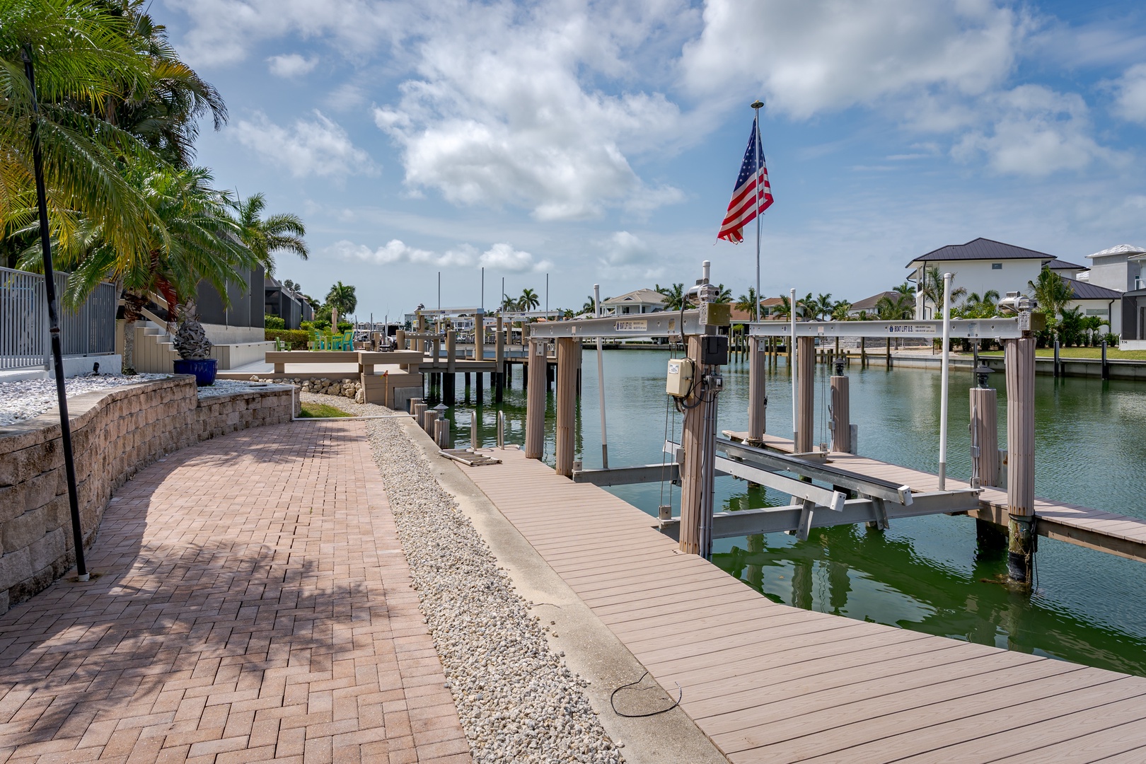 Waterfront property features private boat dock with direct canal access, palm-lined pathways, and coastal neighborhood views.