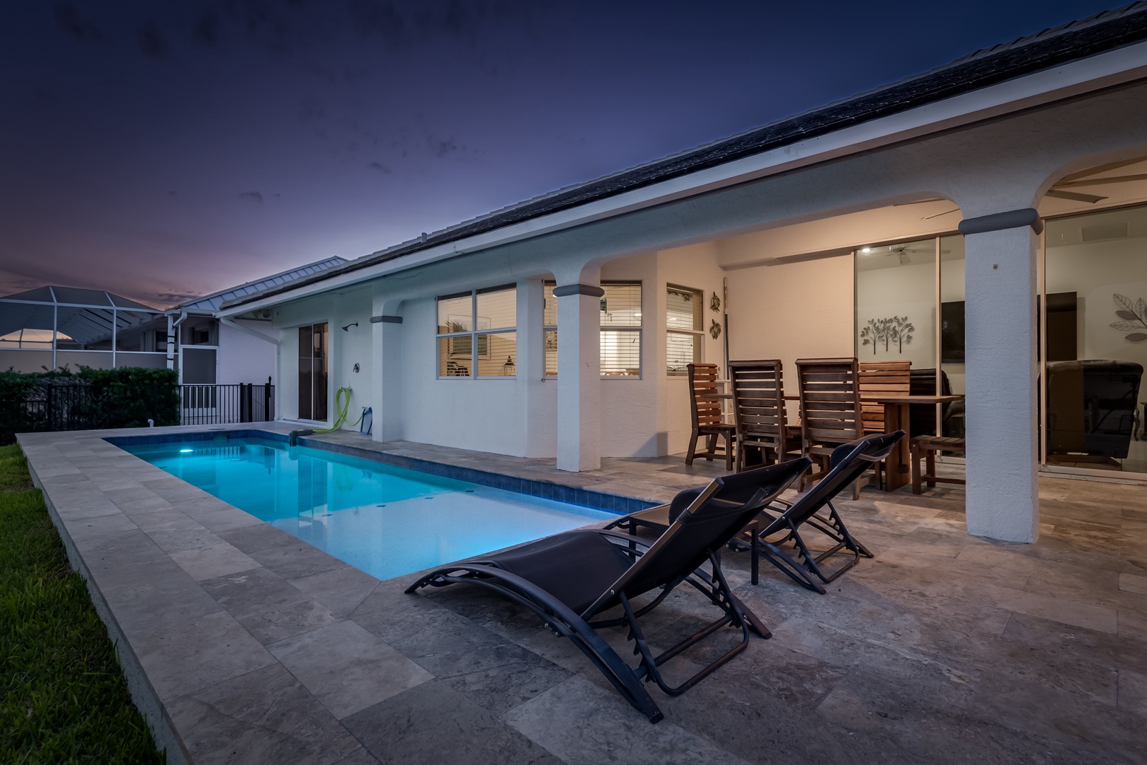 This elegant vacation home features a private pool surrounded by stylish outdoor furnishings, perfect for relaxing under twilight skies. Seamless indoor-outdoor living awaits.