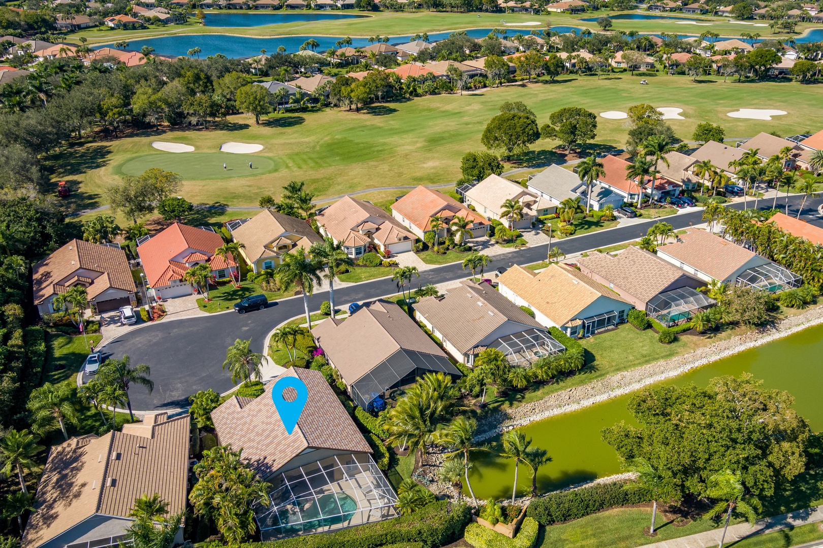 Aerial view of an upscale golf community featuring well-maintained fairways, water features, and luxury homes with pool enclosures.