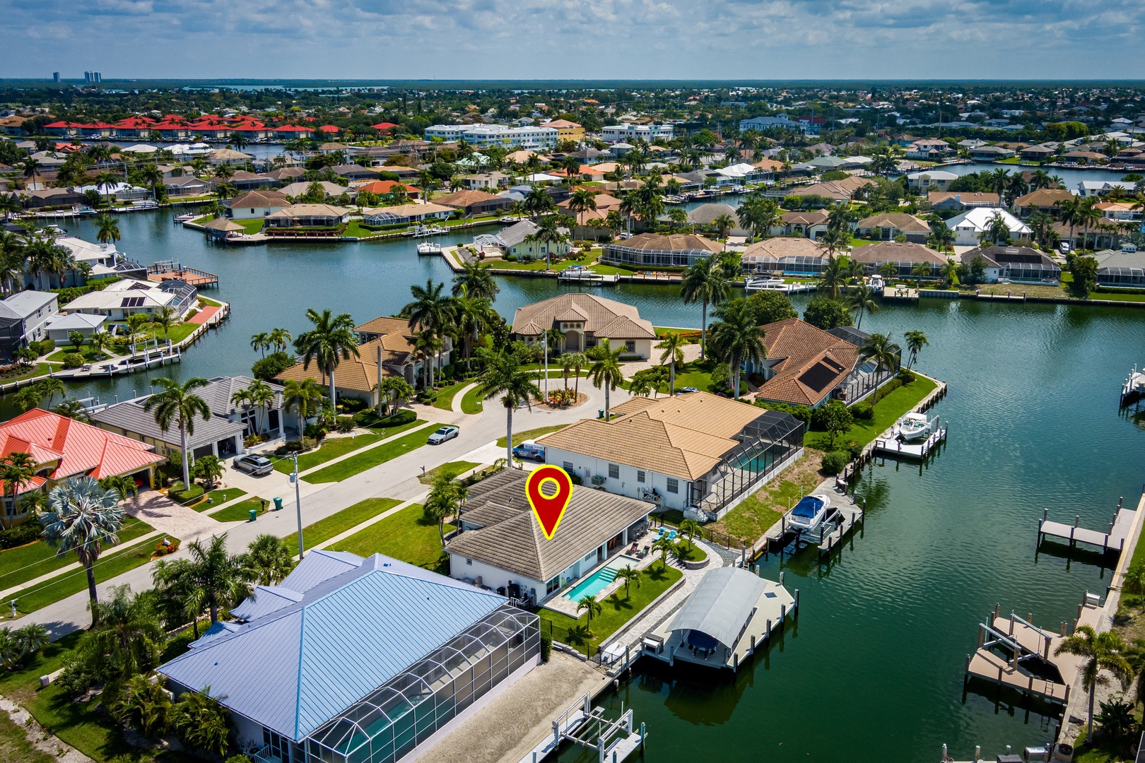 Aerial view of a waterfront vacation rental in a scenic canal-front community with boat docks, swimming pool, and easy access to open waterways.
