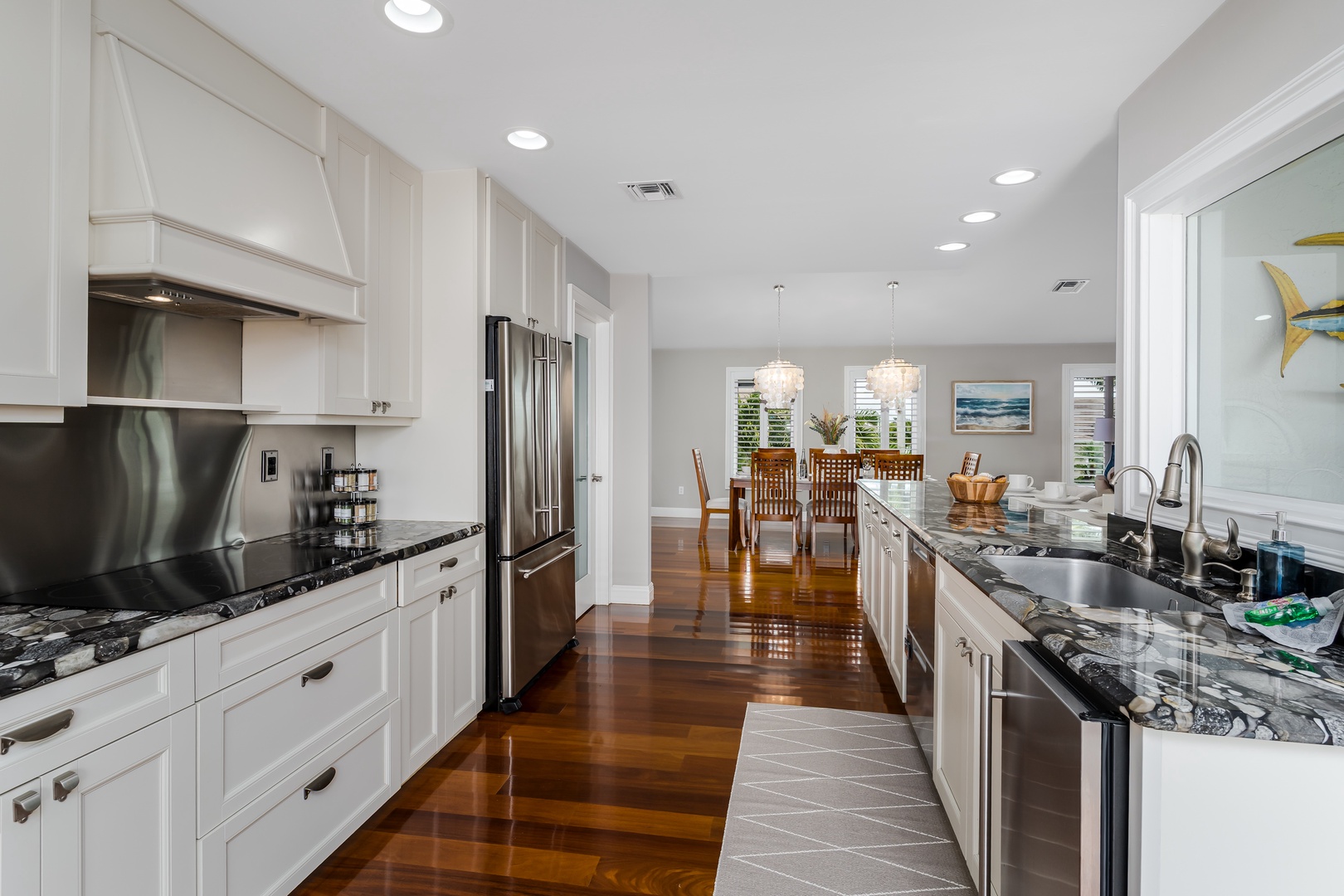 Prepare delicious meals in this elegant kitchen featuring sleek granite countertops, modern stainless appliances, and gleaming hardwood floors that flow into the bright dining space.