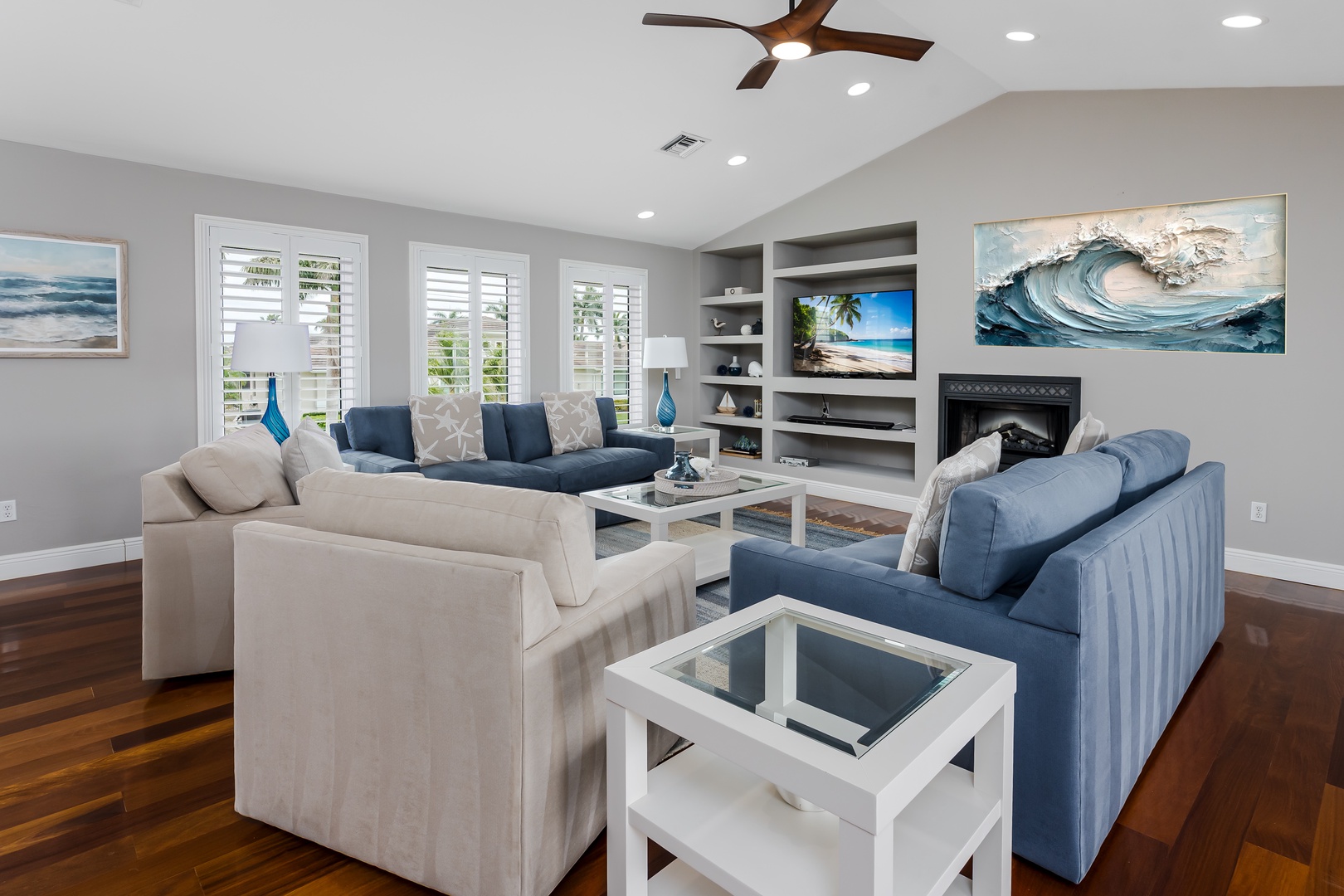Unwind in your bright living room with plush seating, coastal artwork, and a cozy fireplace. Rich wood floors and a ceiling fan complete this inviting retreat.