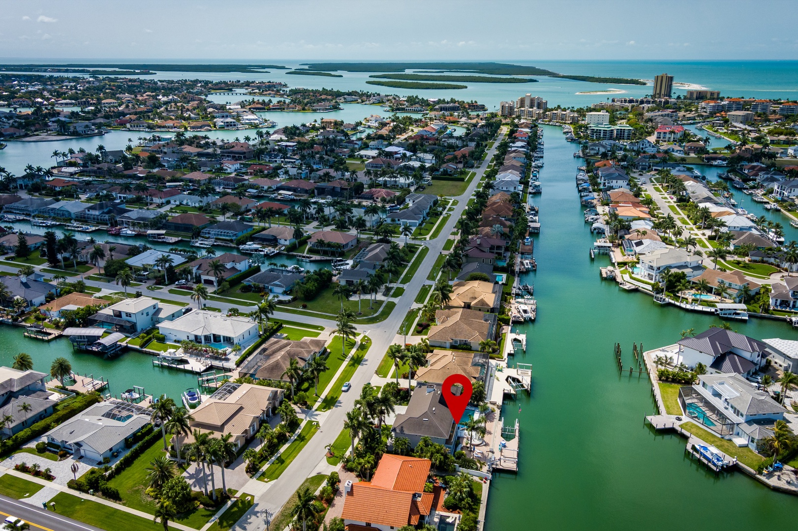 This waterfront property sits on a canal with direct boat access, surrounded by tropical palms and neighboring homes in a serene coastal community beneath azure skies.