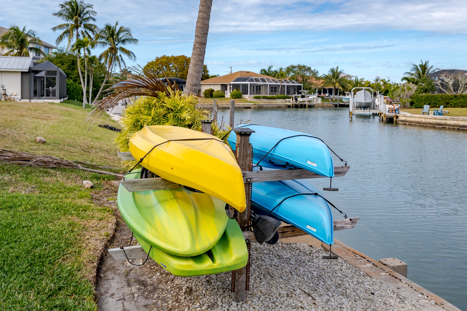 Vibrant kayaks await your next waterfront adventure in this tropical canal setting with lush palm trees.