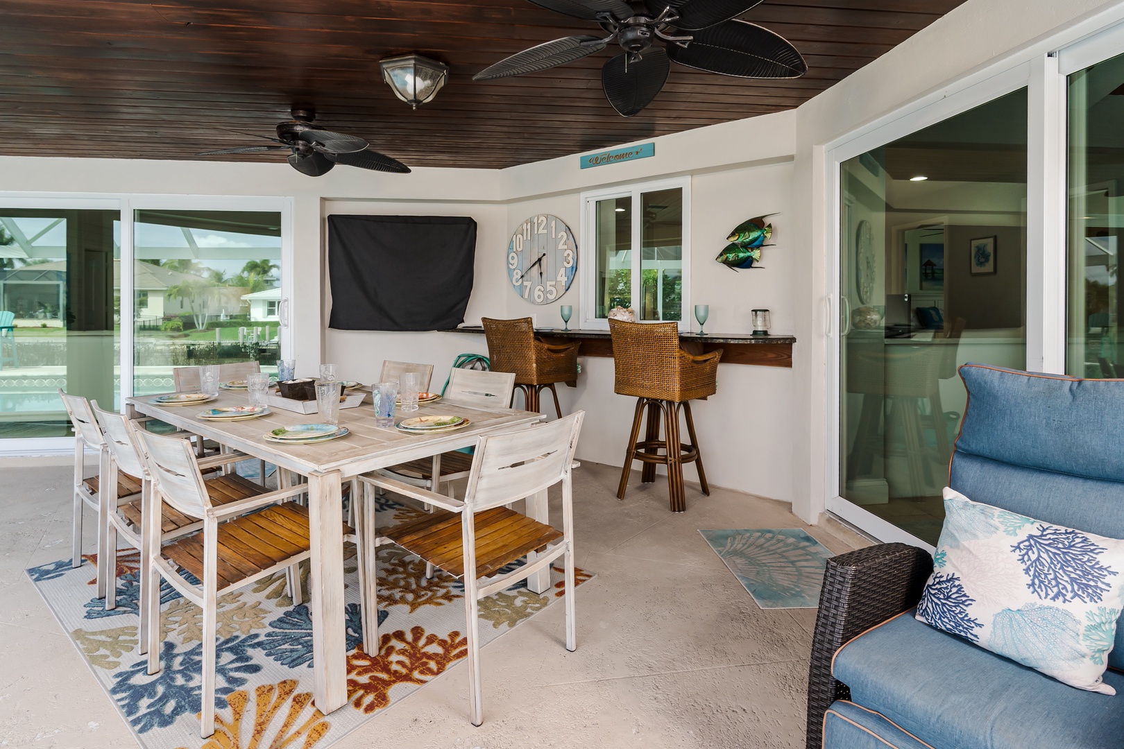 Your covered patio seamlessly blends indoor comfort with outdoor living, featuring a spacious dining table and cozy seating for perfect waterfront relaxation.