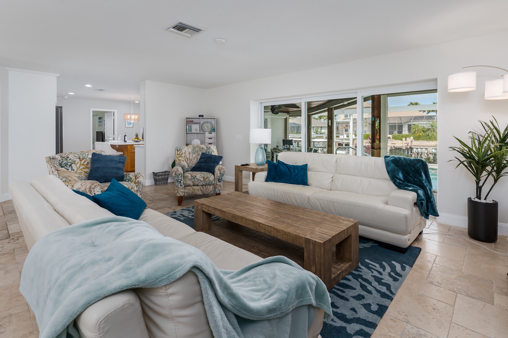 Sink into plush white sofas with ocean-inspired accents in your bright, modern living room, where large windows frame neighborhood views.