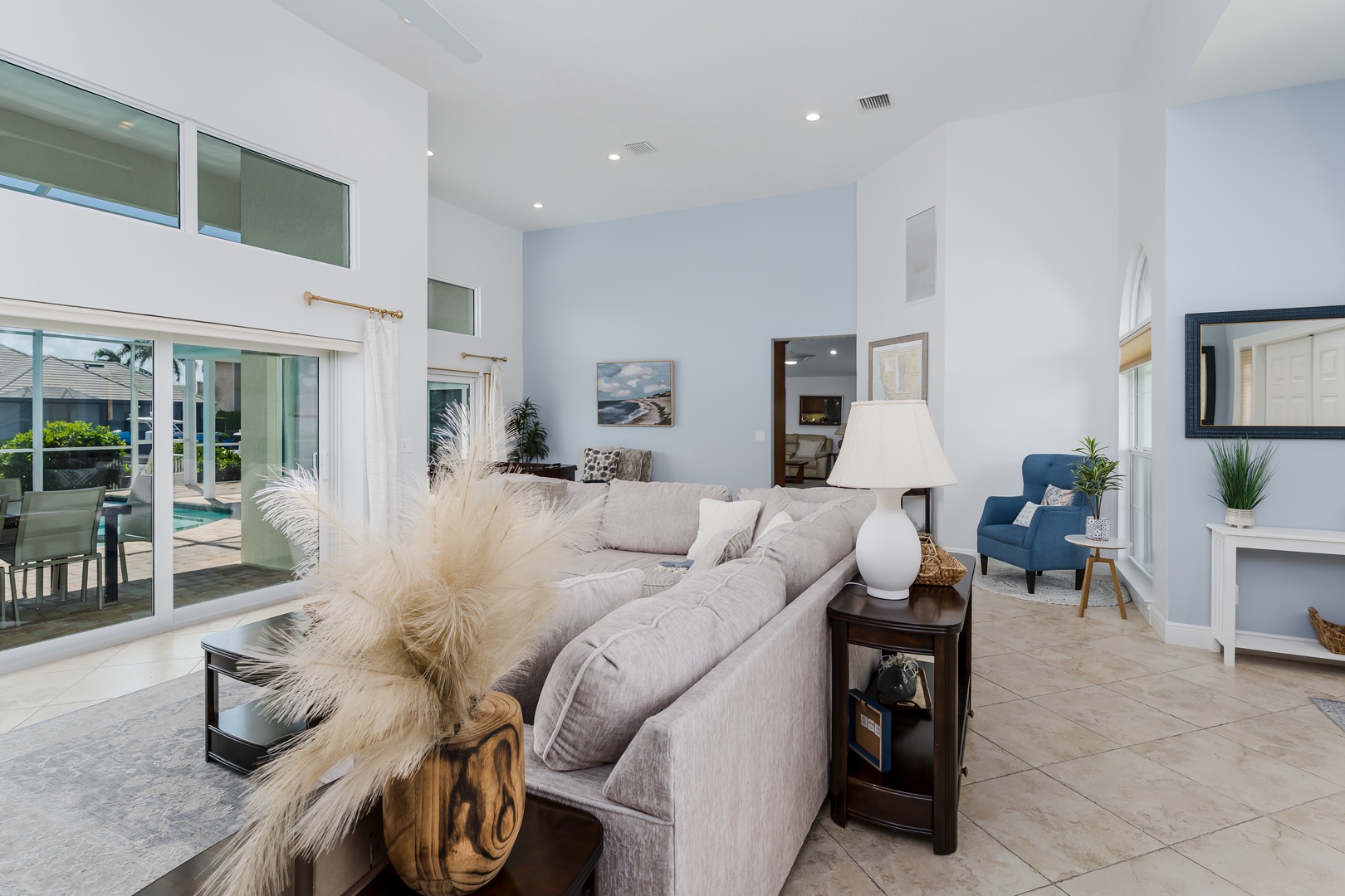 Sink into plush sofas in your bright living space with soaring ceilings and pool views through floor-to-ceiling windows.
