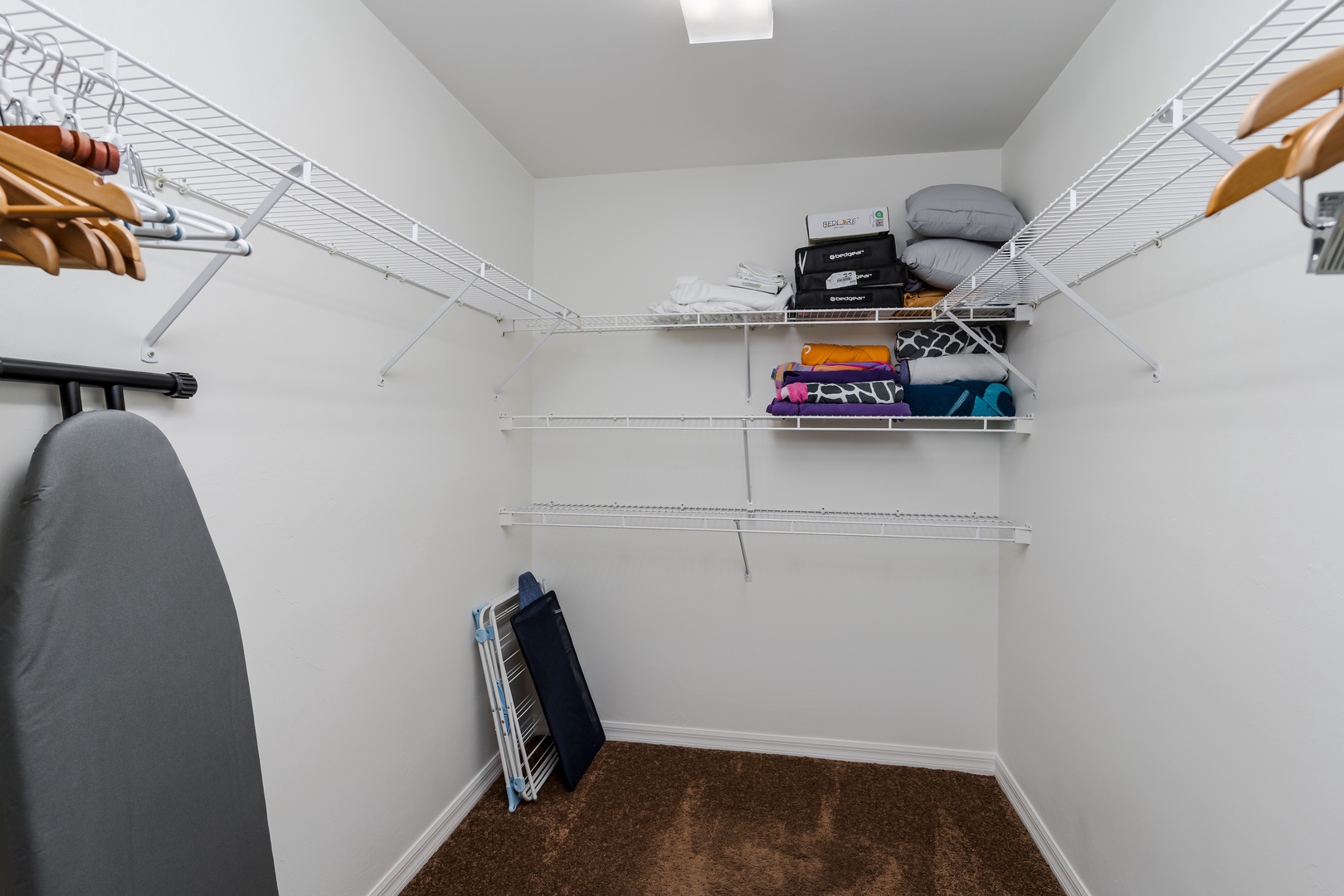 Your spacious walk-in closet with organized wire shelving and an ironing board keeps your belongings perfectly arranged during your stay.