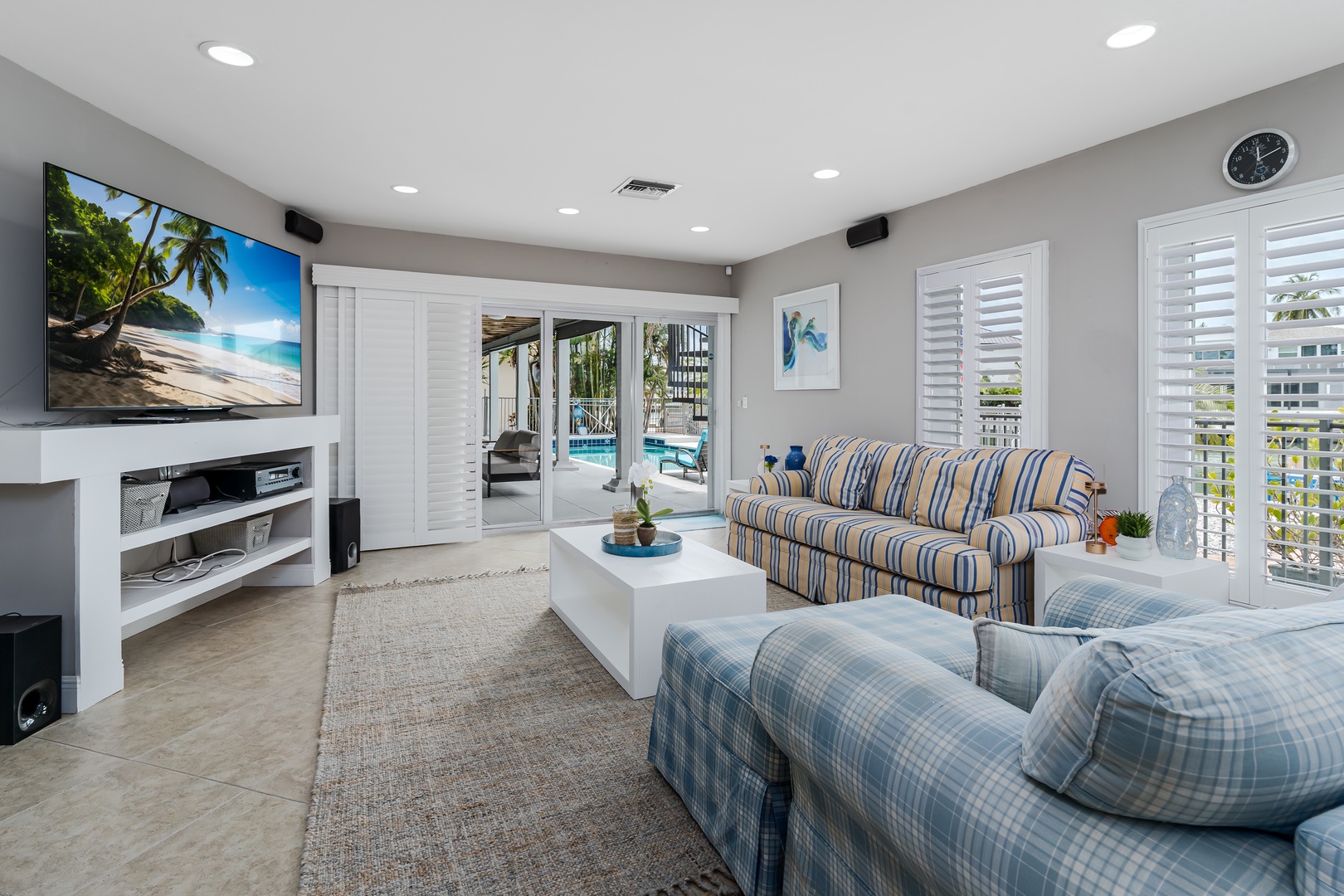 Sink into plush seating and enjoy your favorite shows on the large screen, with pool views just beyond the glass doors inviting relaxation.