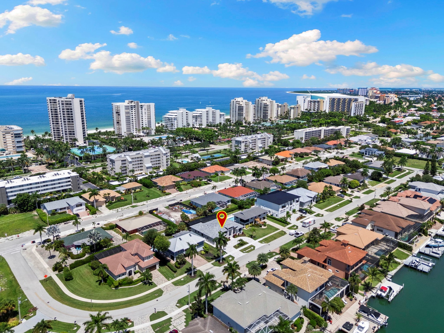 Coastal neighborhood featuring beachfront high-rises, residential homes with palm-lined streets, and canal access—combining urban convenience with seaside living.