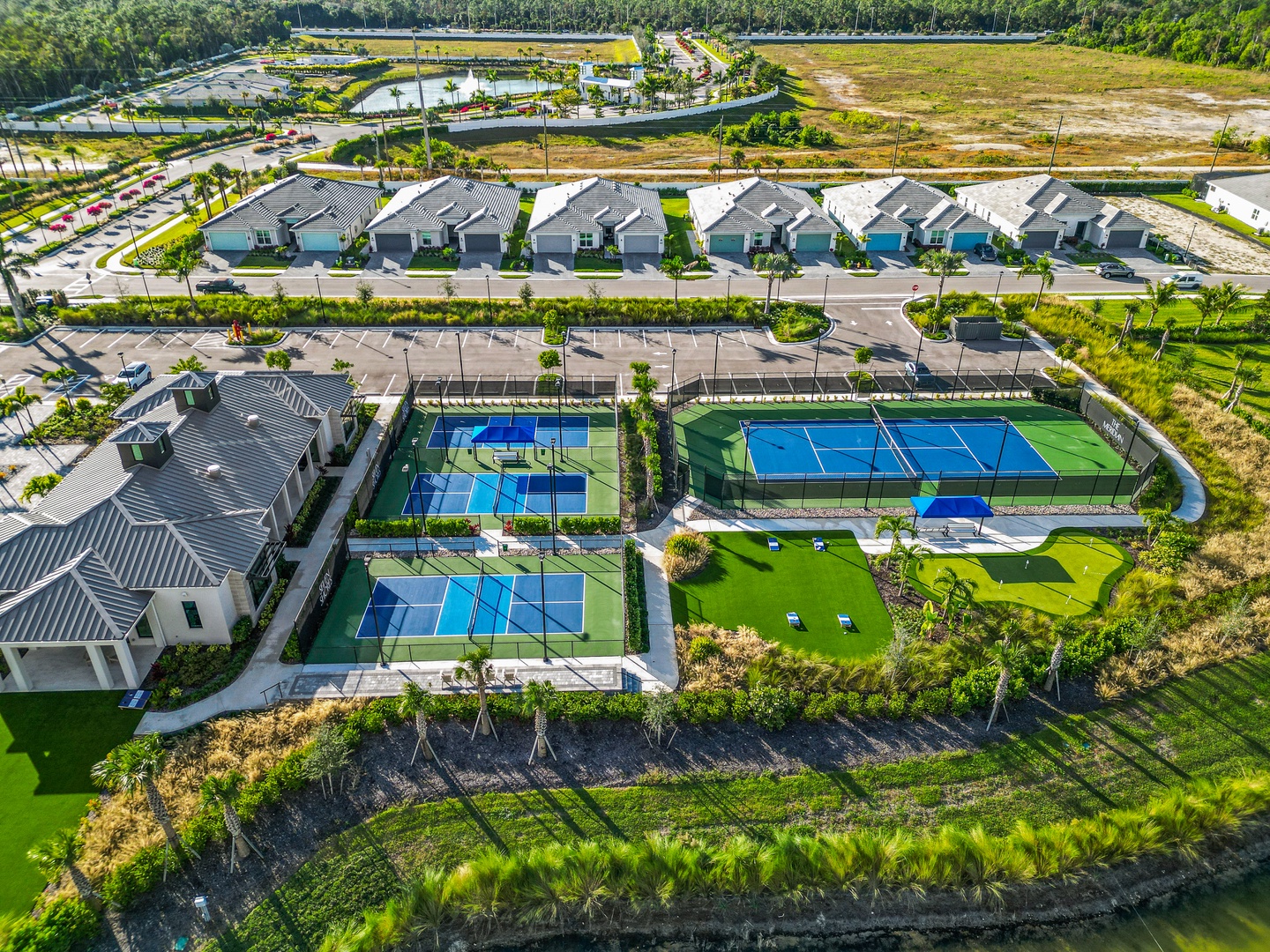 Modern residential community featuring tennis and pickleball courts, surrounded by lush landscaping and neighboring homes.
