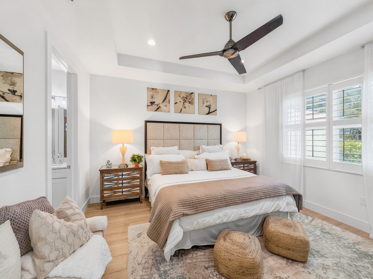 Sink into comfort in this serene bedroom, where crisp linens and warm wood tones create your perfect sanctuary. Natural light floods through plantation shutters as ceiling fans keep you cool.