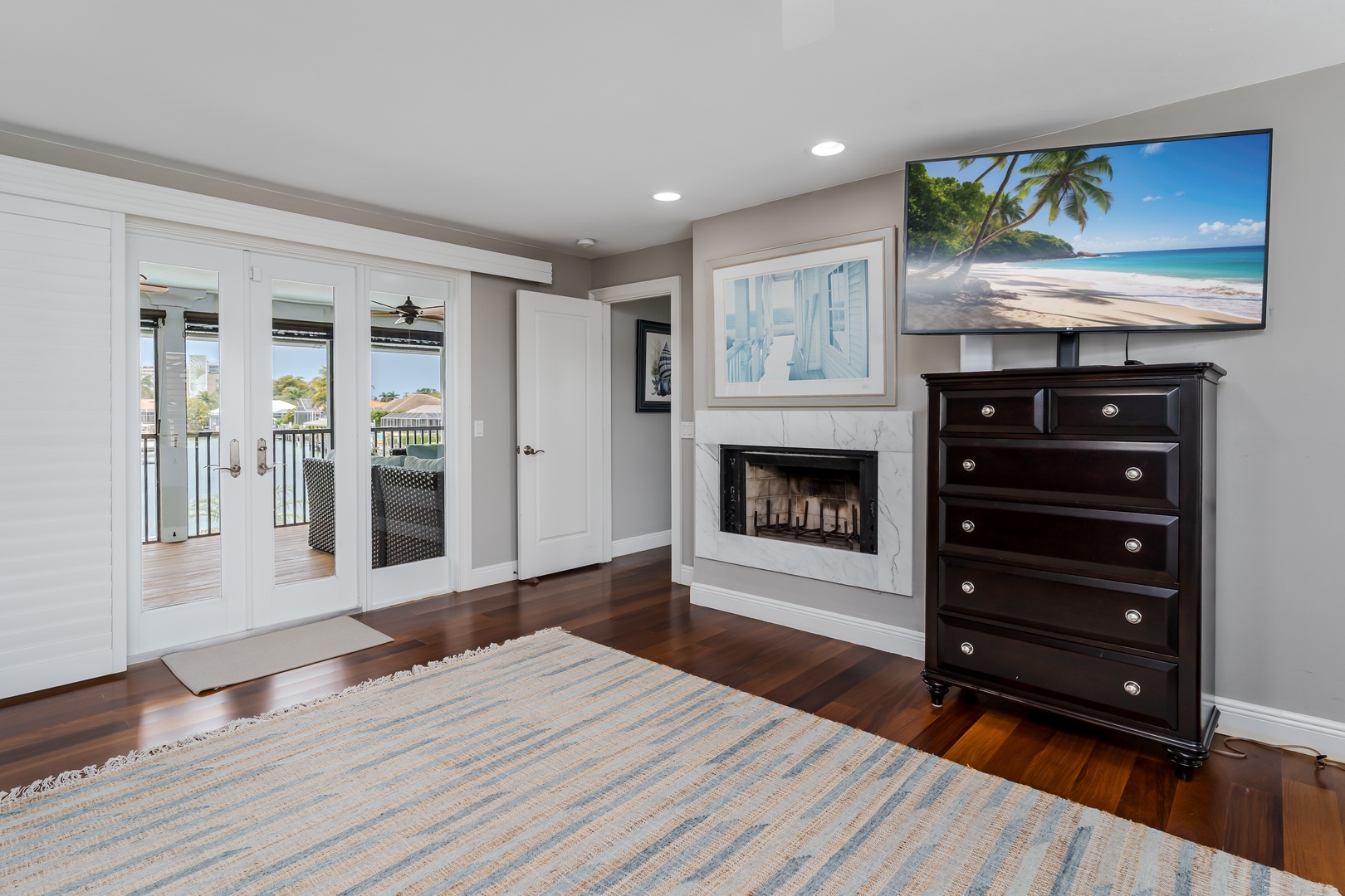 Step into your serene retreat with rich hardwood floors, a cozy fireplace, and balcony doors opening to lovely views. Unwind by the warmth or enjoy tropical scenery on the flat-screen TV.