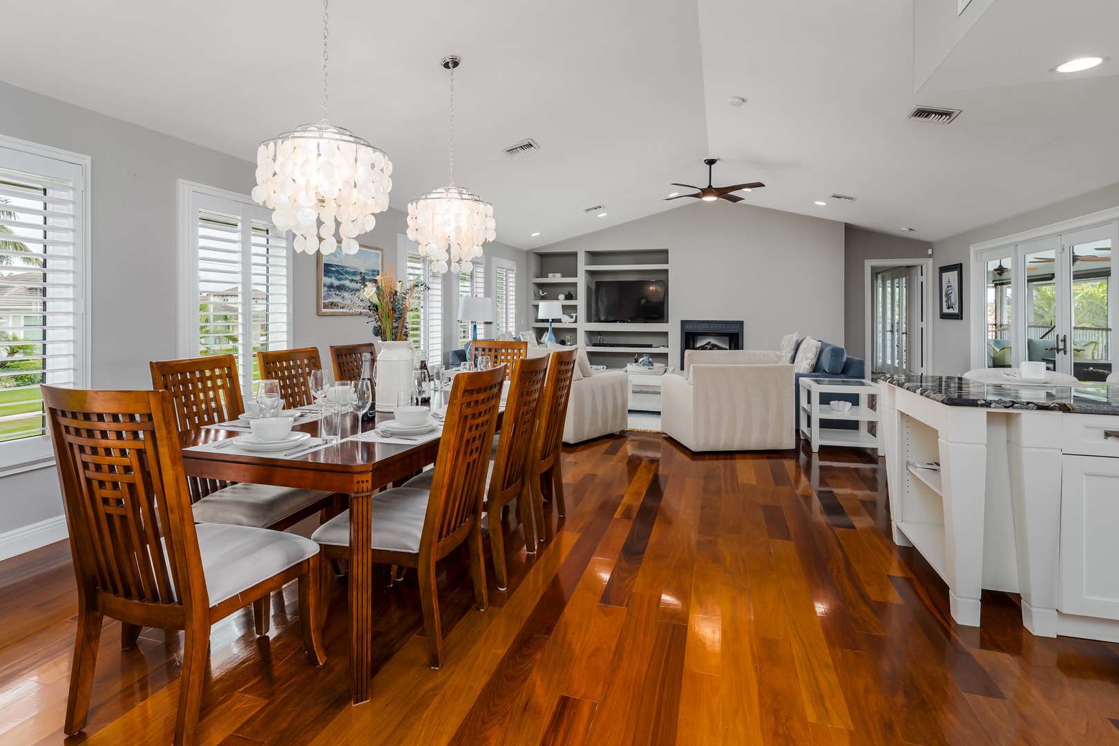 Your dream open-concept space combines dining, kitchen, and living in one beautifully lit room. Warm hardwood floors flow beneath elegant chandeliers, while natural light pours through white shutters. Gather, cook, and relax together.