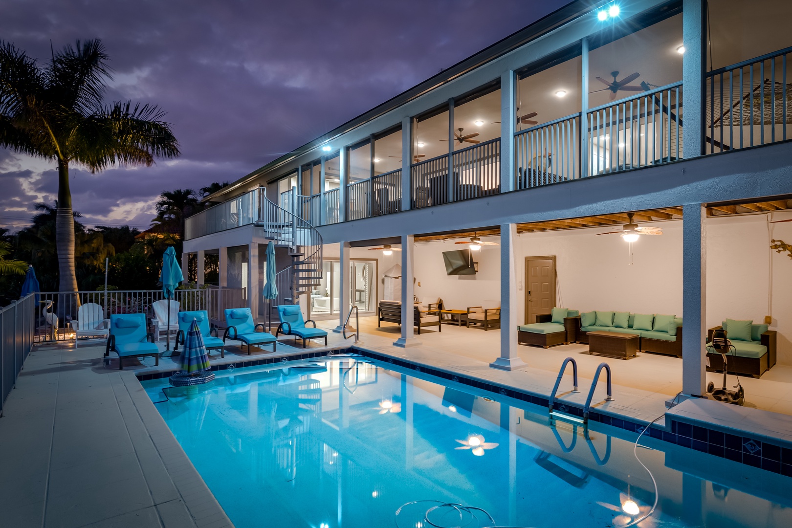The property's illuminated pool and spacious covered patio area create an inviting tropical retreat, framed by swaying palms and serene twilight skies perfect for evening relaxation.