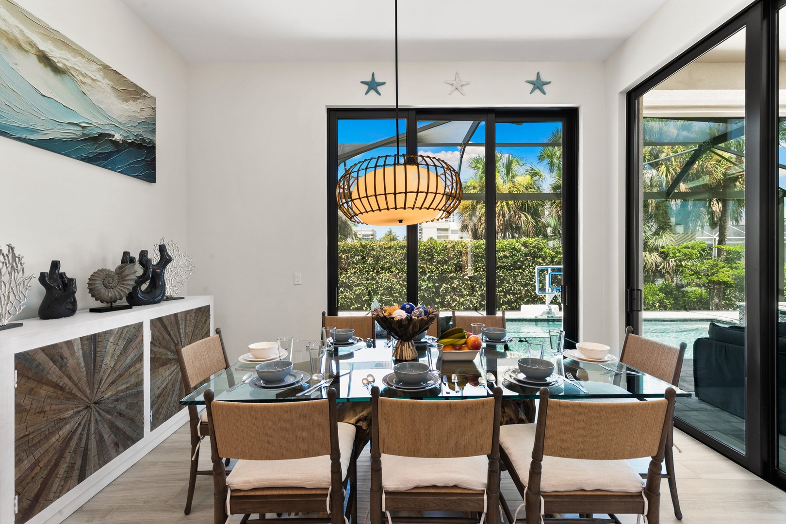 Gather at your elegant dining table with coastal-inspired decor, where palm-fringed views and poolside access create the perfect backdrop for memorable meals together.