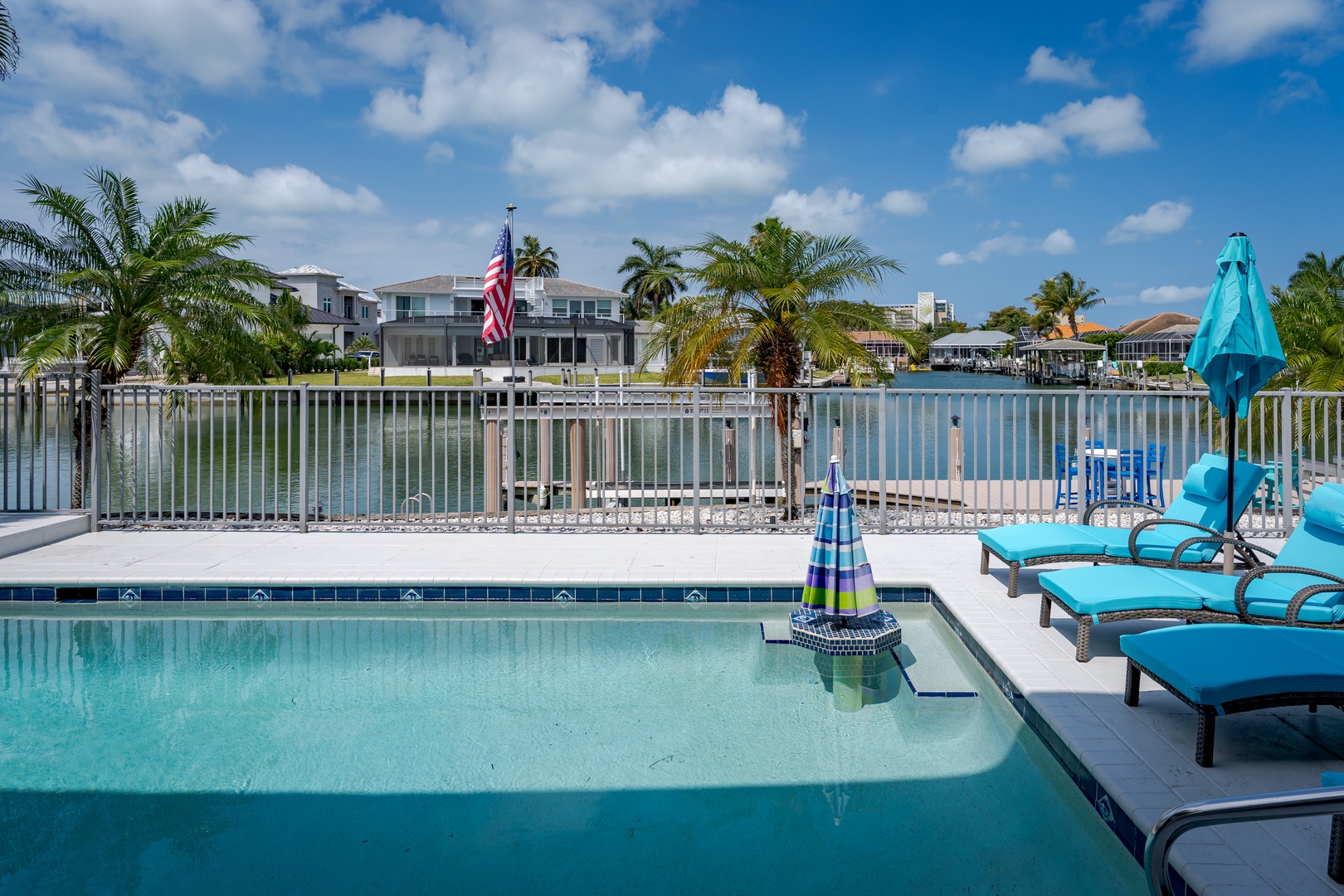 Waterfront vacation rental located in a peaceful canal-front neighborhood with palm trees, boat access, and coastal surroundings visible beyond the pool area.