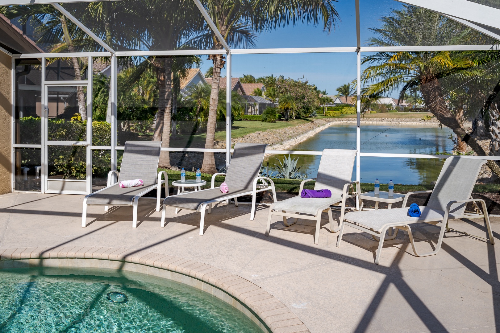 Relax on your private lanai with lounge chairs overlooking the sparkling pool and tranquil canal views framed by swaying palms.