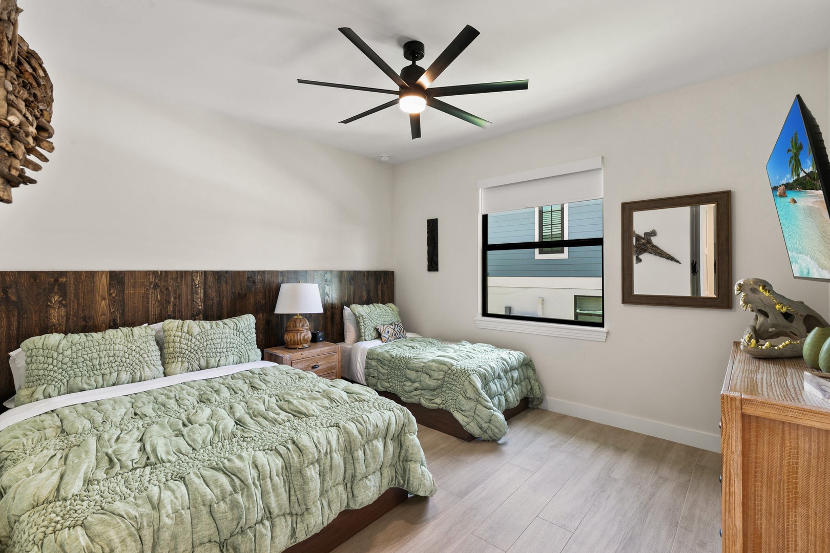 Settle into your cozy bedroom with two comfortable beds dressed in soft green linens. A ceiling fan keeps you cool while natural light filters through the window, creating a peaceful retreat after your adventures.