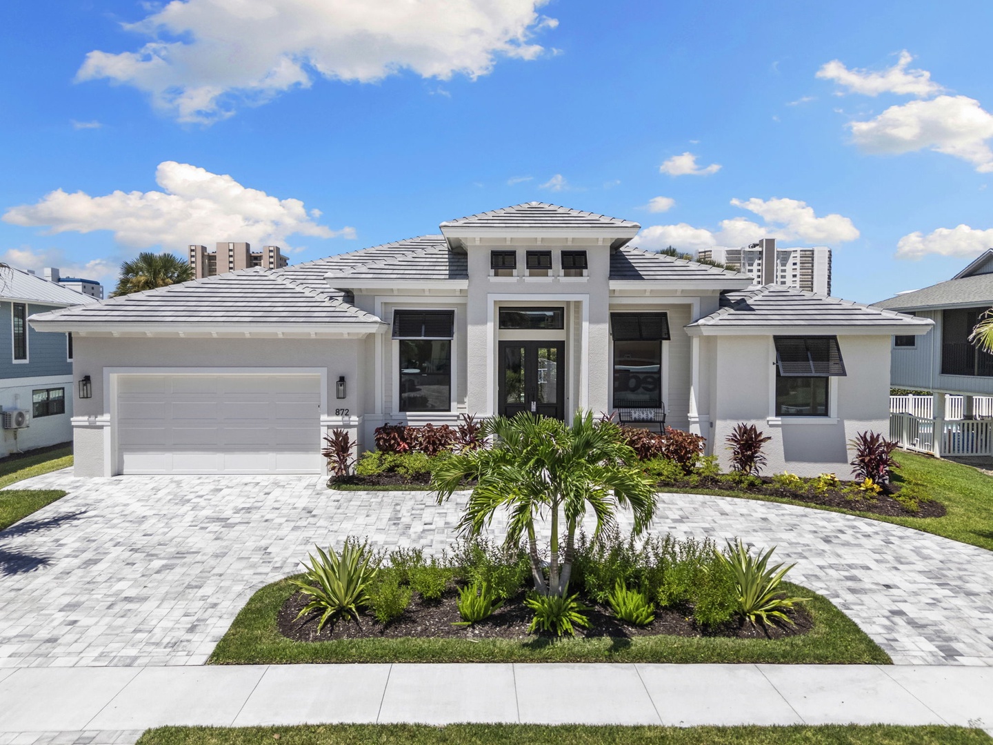 A stunning white coastal home with modern architecture and tropical landscaping marks your arrival spot. This property sits in a tranquil residential neighborhood.