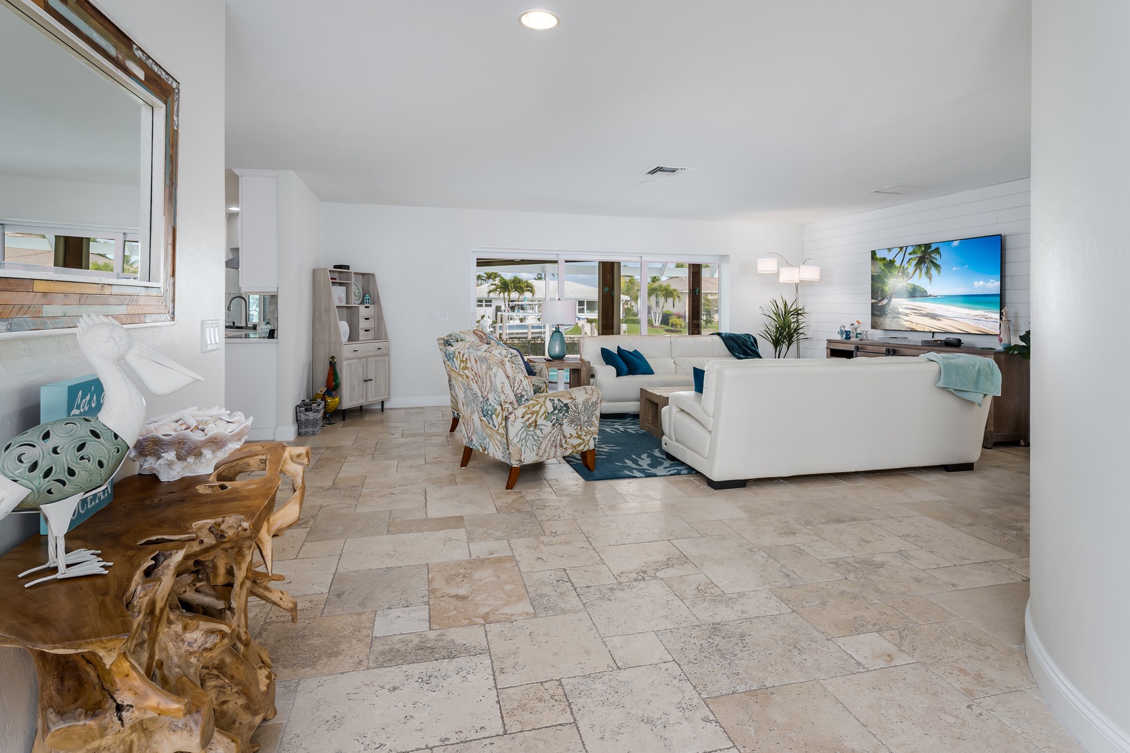 Unwind in your bright, coastal living room with plush seating, tropical decor, and natural stone floors that keep you cool.