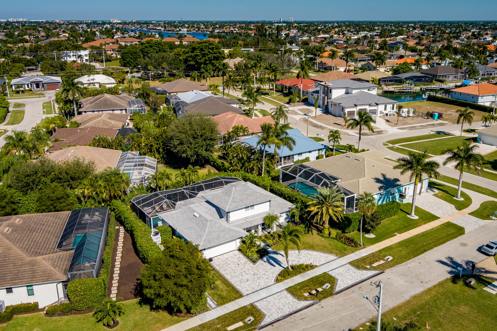 Aerial view of a peaceful residential neighborhood with palm-lined streets and waterfront access in the distance.
