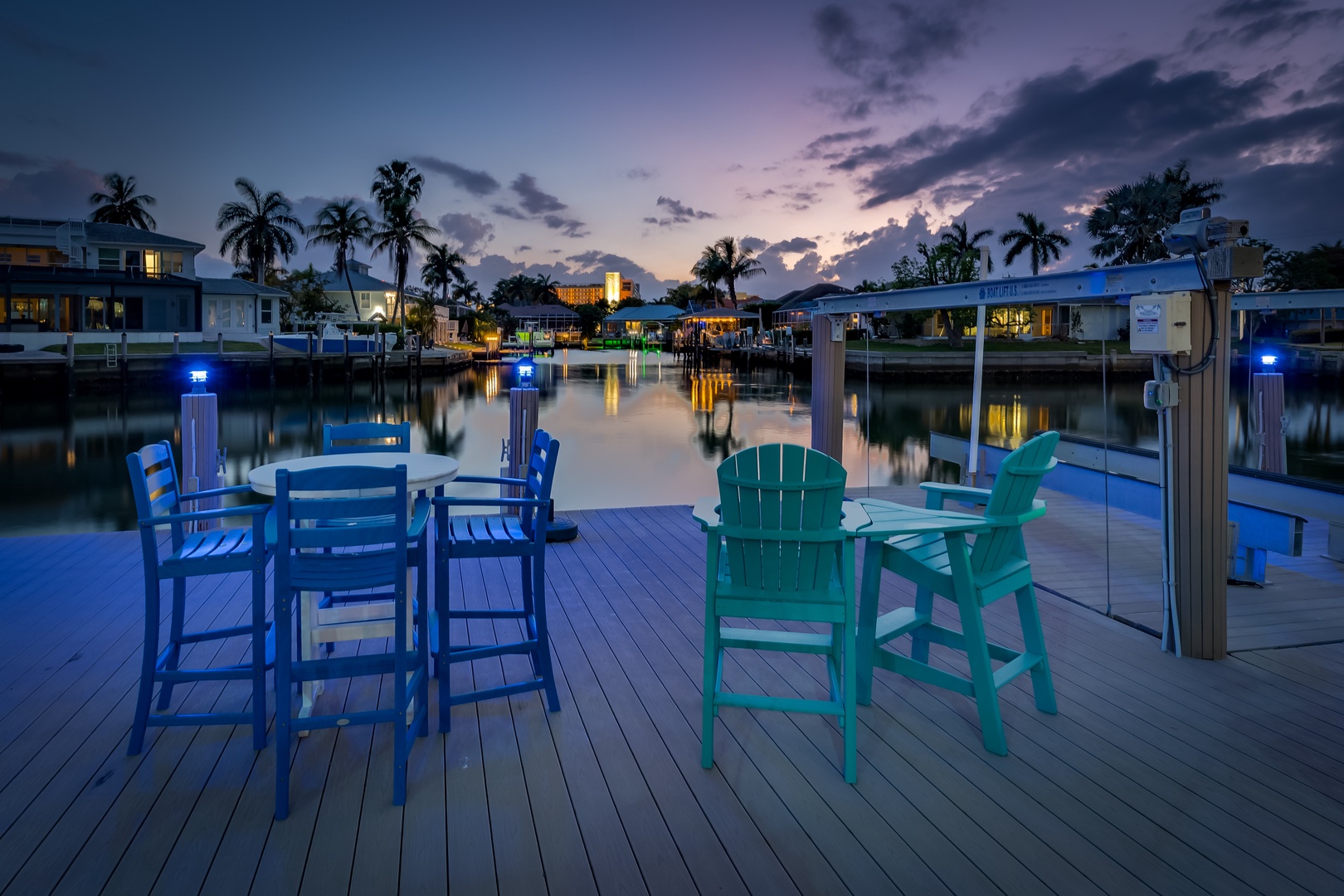 Private waterfront dock with colorful seating overlooking a serene canal and tropical neighborhood at dusk.