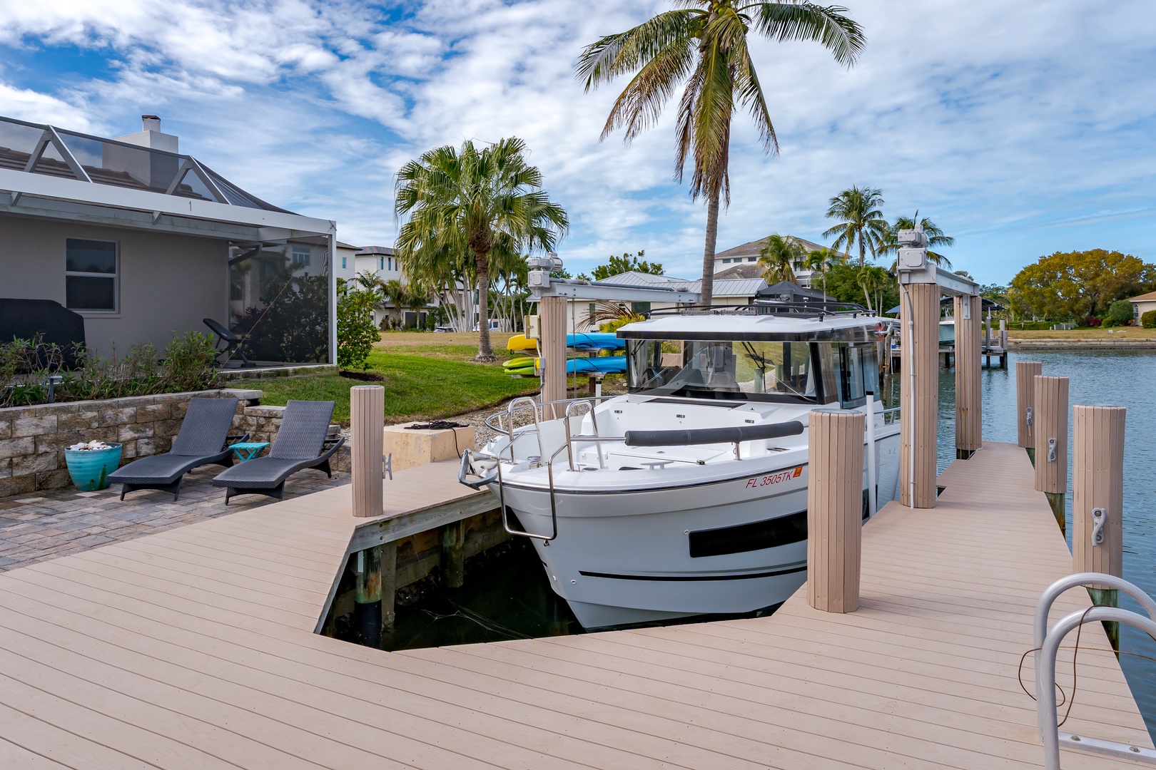 Waterfront property features private dock with boat access, surrounded by palm trees and tropical landscaping in peaceful residential area.