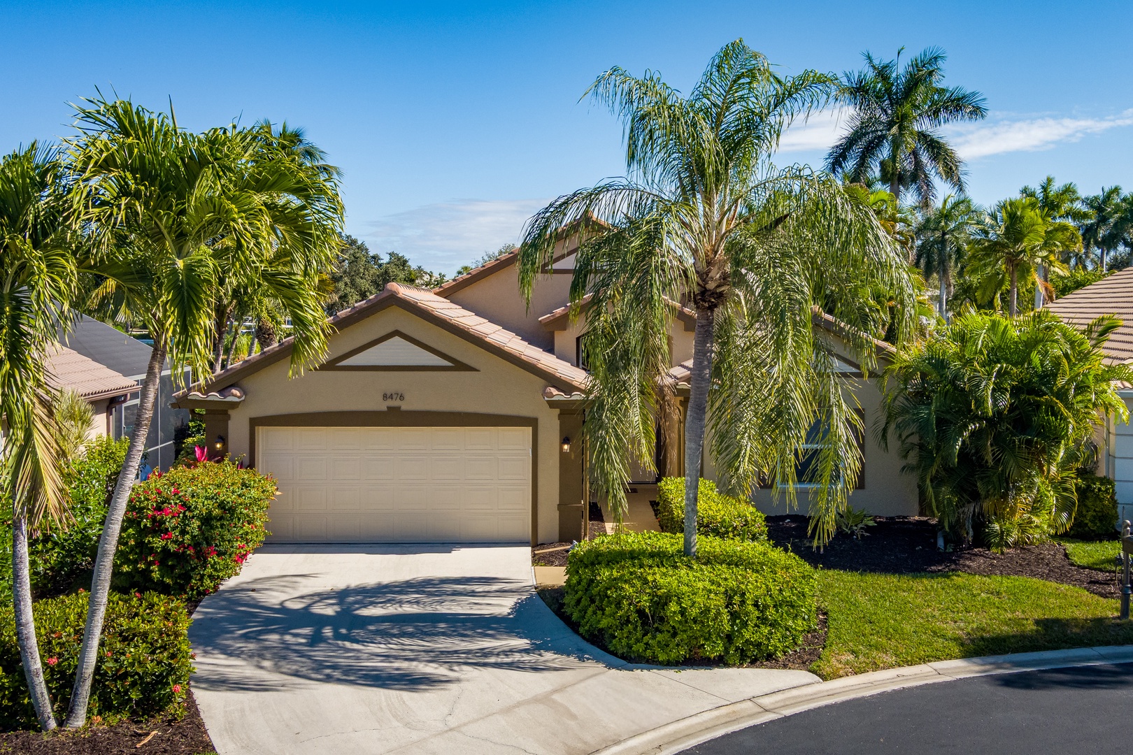 Tropical paradise awaits at this beautiful Florida home, surrounded by swaying palms and lush landscaping in a pristine neighborhood setting.